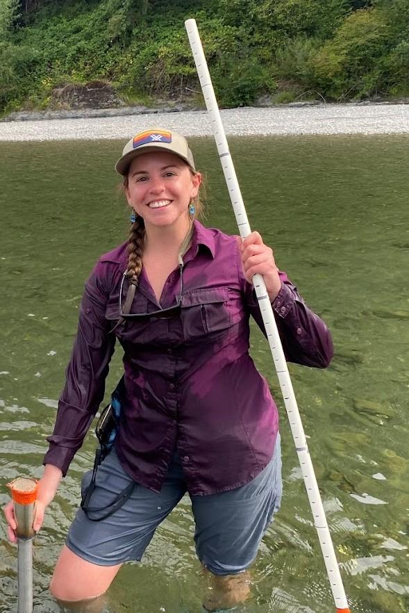 Sydney Jantsch holding a piezometer and steel driving rod, used to measure hyporheic temperature patterns beneath the riverbed.