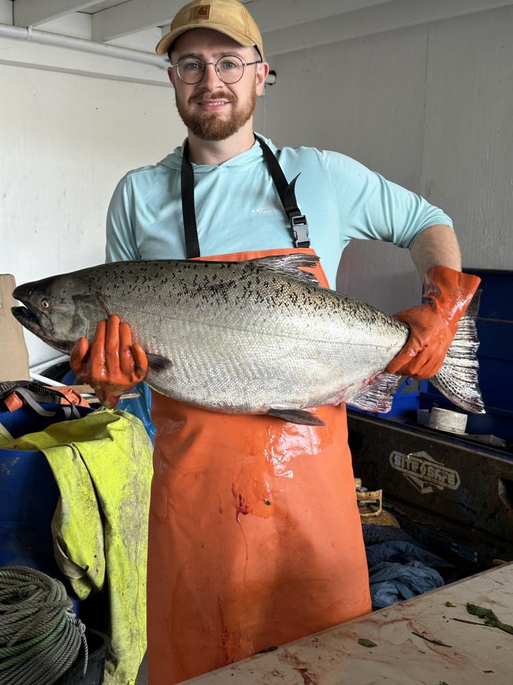 Ryan Harris poses with a big Chinook salmon before taking genetic samples during commercial Chinook season.
